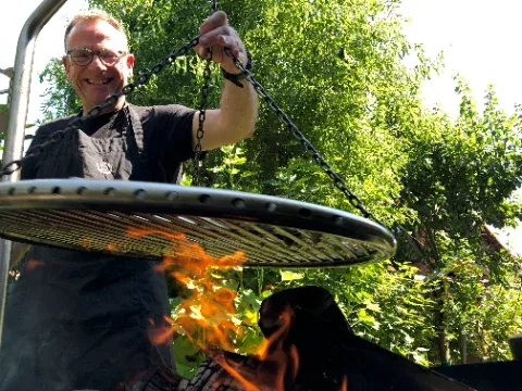 Bernd am Schwenkgrill über offenem Feuer